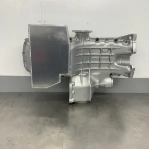 Import placeholder for 2074 is a silver automotive gearbox case featuring a flat rectangular metal plate on one side, shown on a grey metallic surface with a white background.