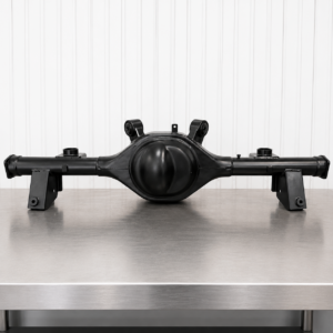 The HQ-WB Saloon Ford 9" Diff Housing, a black metal automotive axle housing with bracket mounts, is shown on a stainless steel table against a white vertically lined wall.
