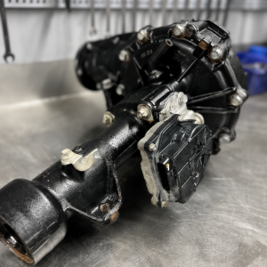 An N70 Hilux Rebuilt Front Exchange diff sits on a workbench in a workshop, with spanners hanging on the wall in the background and a blue container nearby.