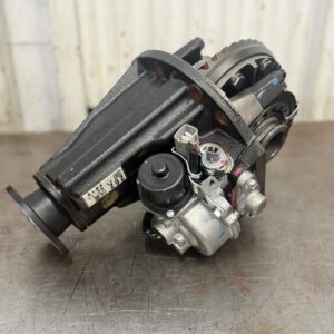 A Toyota HZJ70 Series 4.3 New Genuine Front Locker Diff Exchange with metal gears, housing, and actuator sits on a workbench against a light-coloured, vertically panelled wall.