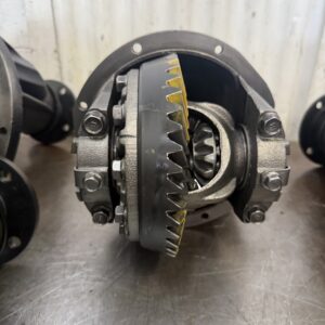 Close-up of a Mazda Bounty 4WD 4.44 Rebuilt Front Exchange Diff with yellow marking compound on the gear teeth, placed on a metallic surface against a corrugated background.